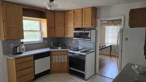 Kitchen with white appliances, a sink, light countertops, light flooring, and brown cabinetry