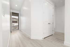 Hallway with light wood-style floors, baseboards, and recessed lighting