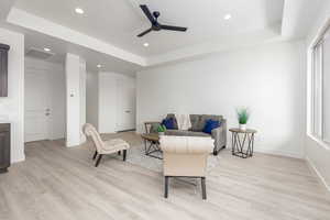 Sitting room with ceiling fan, a raised ceiling, light wood finished floors, baseboards, and recessed lighting