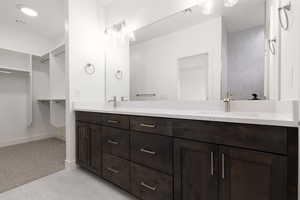 Bathroom with double vanity, baseboards, and a spacious closet