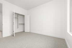 Unfurnished bedroom featuring light colored carpet, baseboards, and a closet