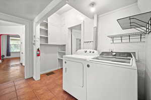 Laundry area with washer and dryer and light tile patterned flooring