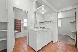 Laundry room featuring washer and dryer, light tile patterned floors, and light colored carpet