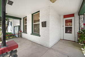 Doorway to property featuring a porch and brick siding