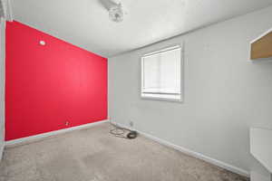Spare room with carpet flooring, baseboards, and a textured ceiling