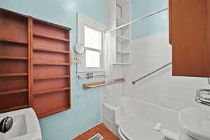 Full bathroom with tile walls, toilet, tile patterned floors, and shower / tub combo