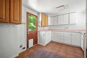 Kitchen with light tile patterned flooring, light countertops, and heating unit
