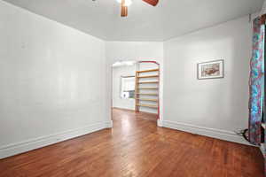 Spare room featuring a ceiling fan, hardwood / wood-style flooring, baseboards, and arched walkways