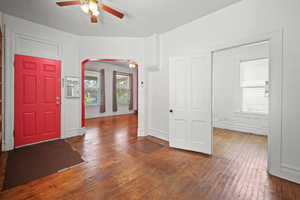 Foyer entrance featuring a ceiling fan, hardwood / wood-style floors, arched walkways, and baseboards