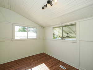 Spare room with lofted ceiling, baseboards, and dark wood-style flooring