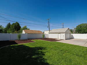 View of yard featuring a garage, an outbuilding, and concrete driveway