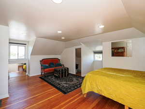 Bedroom with hardwood / wood-style flooring, lofted ceiling, multiple windows, recessed lighting, and baseboards