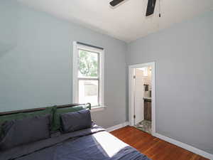 Bedroom with hardwood / wood-style flooring, baseboards, ensuite bath, and ceiling fan