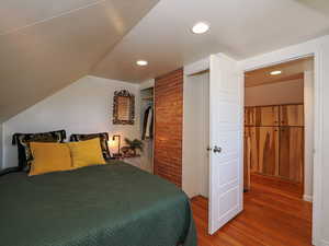 Bedroom with wood finished floors, recessed lighting, vaulted ceiling, and a closet