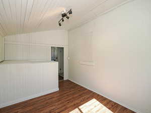 Unfurnished room with wood finished floors and lofted ceiling