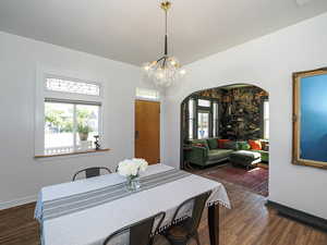 Dining room featuring arched walkways, wood finished floors, baseboards, and a chandelier