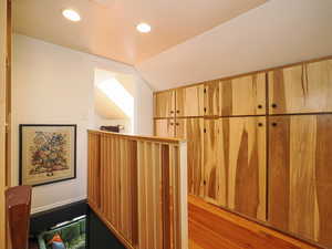 Corridor with wood finished floors, lofted ceiling, and recessed lighting
