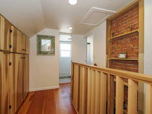 Corridor featuring dark wood-style floors, baseboards, attic access, and vaulted ceiling
