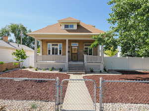 Bungalow featuring a gate, a porch, brick siding, and a fenced front yard