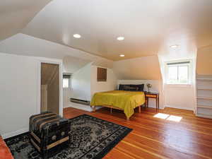 Bedroom with baseboard heating, baseboards, hardwood / wood-style floors, vaulted ceiling, and recessed lighting
