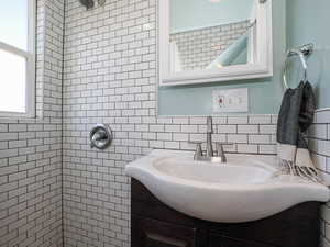 Full bathroom with tiled shower, vanity, and tile walls