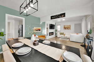 Dining area with wood finished floors, a textured ceiling, a glass covered fireplace, built in features, and baseboards