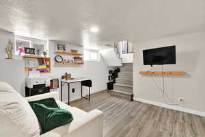Living room featuring a textured ceiling, wood finished floors, baseboards, and stairway
