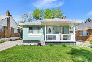 Bungalow featuring covered porch, a front lawn, a chimney, and a shingled roof