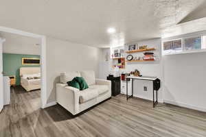 Living area with light wood-style floors, baseboards, and a textured ceiling