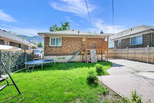 Rear view of property with a trampoline, a patio, brick siding, and a mountain view