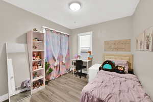 Bedroom with light wood-style floors, an office area, and a textured ceiling