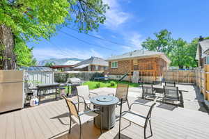 Wooden terrace featuring area for grilling, a fenced backyard, a playground, a trampoline, and an outdoor fire pit