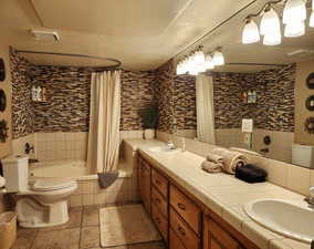 Full bathroom featuring double vanity, tiled shower / bath, and a textured ceiling