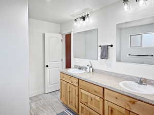 Full bathroom featuring double vanity and baseboards