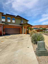 View of front of property featuring an attached garage, concrete driveway, stucco siding, and a mountain view