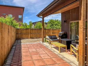 Fenced backyard featuring a patio, a grill, and an outdoor hangout area