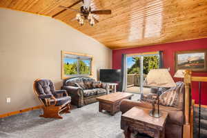 Carpeted living room with wooden ceiling, vaulted ceiling, ceiling fan, and baseboards