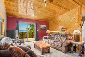 Carpeted living area featuring wooden ceiling, lofted ceiling, and wood walls