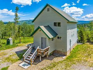 Back of house with a view of trees and metal roof