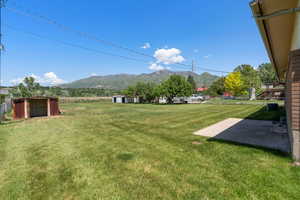 View of grassy yard featuring a mountain view, a patio, and central AC unit