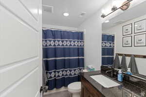 Bathroom with vanity, toilet, and curtained shower