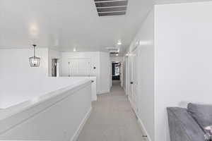 Hallway featuring baseboards and light carpet