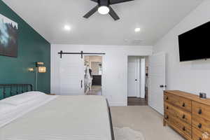 Bedroom with a barn door, light colored carpet, baseboards, recessed lighting, and ceiling fan
