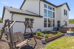 Rear view of house with a vegetable garden, stucco siding, a shingled roof, and cooling unit