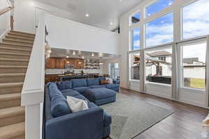 Living room with stairs, healthy amount of natural light, wood finished floors, recessed lighting, and baseboards