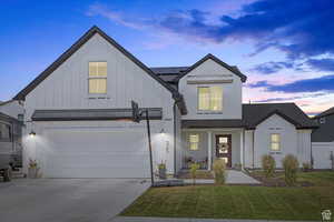 Modern farmhouse style home featuring board and batten siding, concrete driveway, a garage, covered porch, and a front lawn