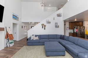 Living room with a towering ceiling, stairway, dark wood-style flooring, baseboards, and recessed lighting