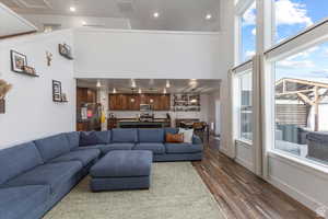 Living room featuring a towering ceiling, dark wood-style floors, healthy amount of natural light, recessed lighting, and baseboards