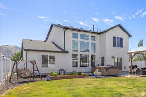 Rear view of house featuring a hot tub, stucco siding, a patio area, and a mountain view