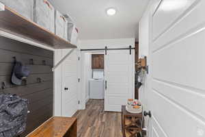 Mudroom featuring washer / clothes dryer, dark wood-type flooring, and a barn door